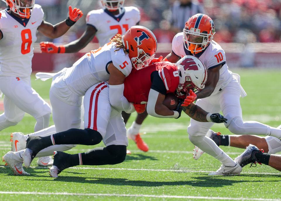 Illinois linebacker Calvin Hart Jr. (5) and defensive back Tahveon Nicholson (10) tackle Wisconsin running back Braelon Allen on Saturday, a day the Illini held the Badgers to 21 rushing yards on 16 carries.