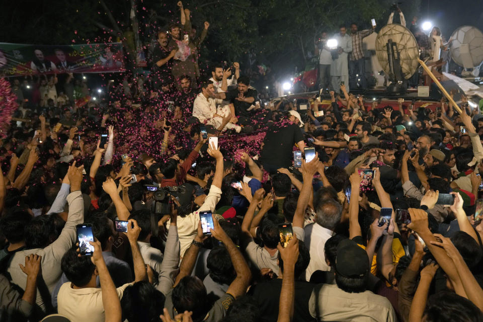 Supporters shower a vehicle with rose petals carrying former Prime Minister Imran Khan to greet him upon his arrival at his home in Lahore, Pakistan, Saturday, May 13, 2023. A high court in Islamabad on Friday granted Khan protection from arrest in a graft case and ordered him freed on bail. (AP Photo/K.M. Chaudary)