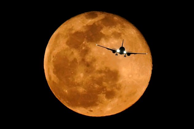 A plane flying in front of the full moon