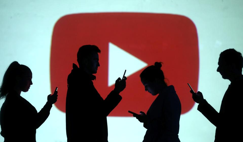 FILE PHOTO: Silhouettes of mobile users are seen next to a screen projection of Youtube logo in this picture illustration taken March 28, 2018.  REUTERS/Dado Ruvic/Illustration