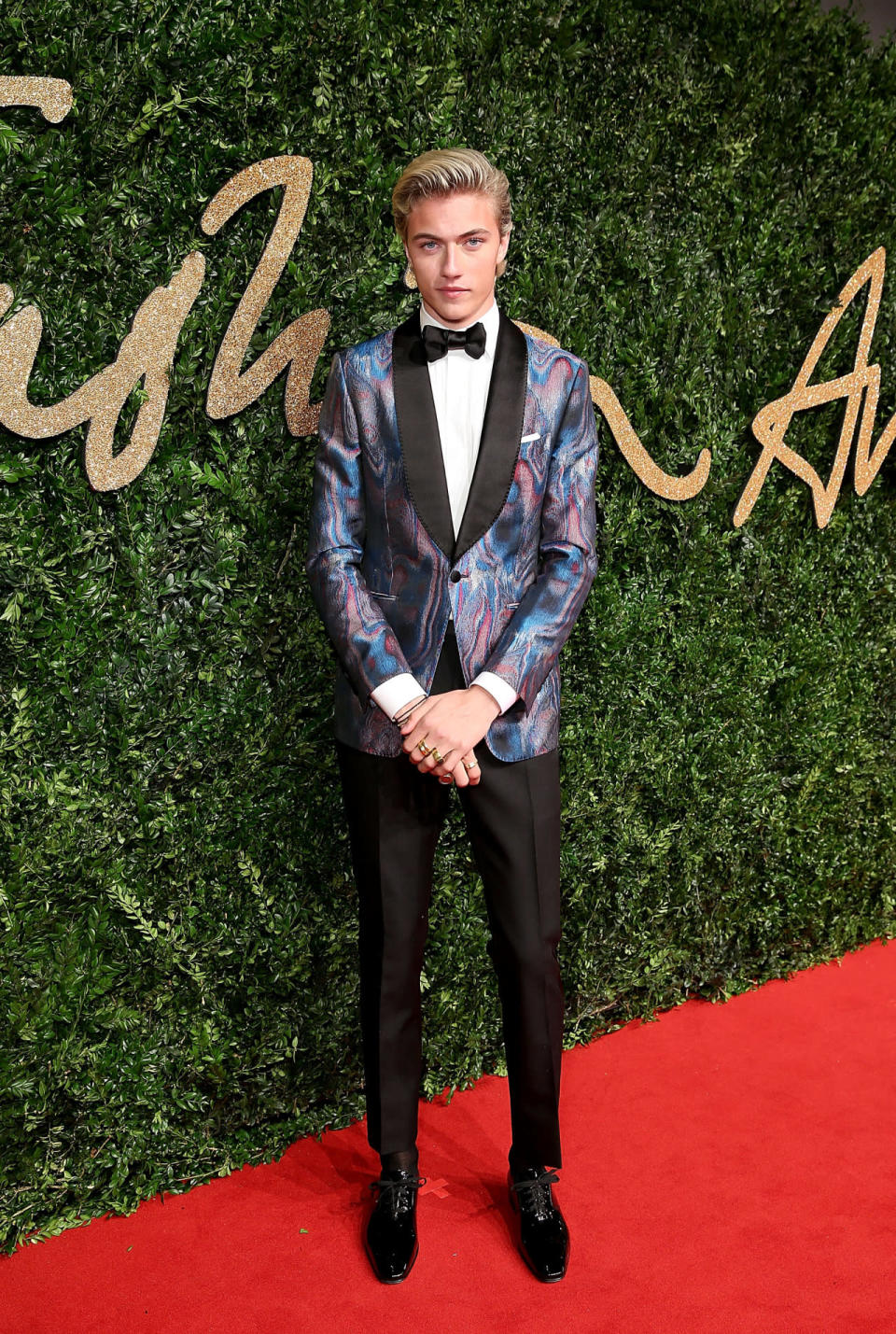 Lucky Blue Smith in a holographic tuxedo jacket and black pants.