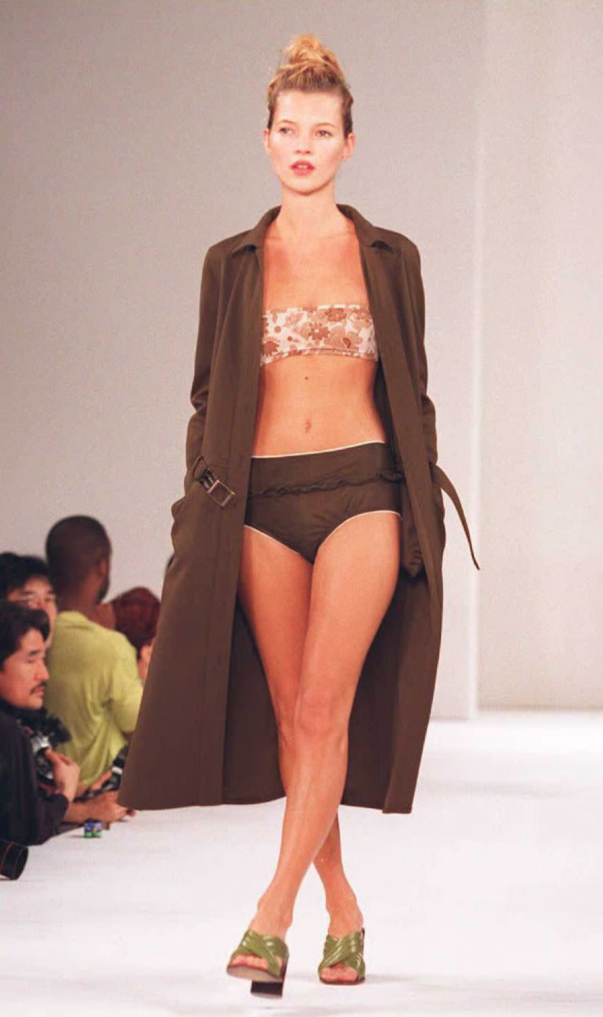 Supermodel  Kate Moss wears a brown swimsuit with a flowered top and a long coat during the Miu Miu Spring/Summer 1996 fashion show 02 November in New York.