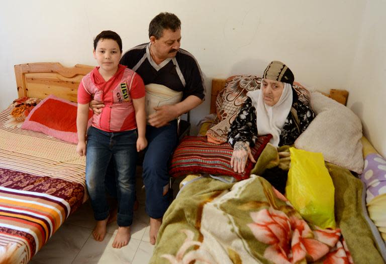 Syrian refugee Fares al-Bashawat (C) sits with his 10-year-old son Nemr (L) and his mother at a house in the Egyptian port city of Alexandria on April 23, 2015