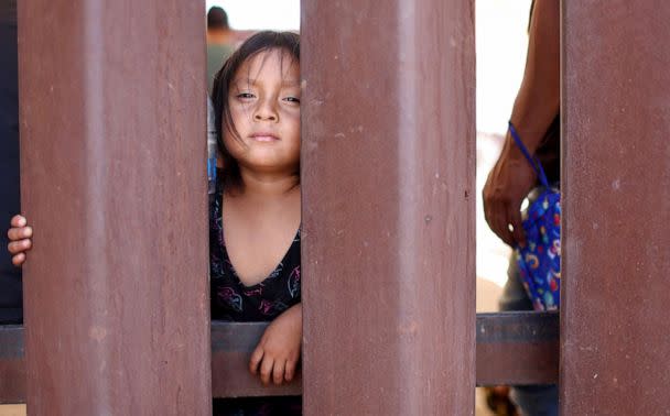 PHOTO: Ecuadoran immigrant Janina, 4, stands by her father and other immigrants seeking asylum in the U.S. awaiting processing by Border Patrol agents after crossing into Arizona from Mexico, on May 10, 2023 in Yuma, Ariz. (Mario Tama/Getty Images)