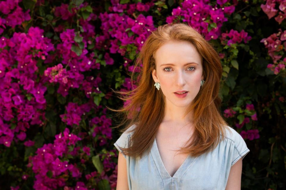 A redheaded model named Laura from Virginia, US, poses against a flowered bush