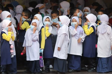 Students cover their faces with masks at a school as haze shrouds Kuala Lumpur