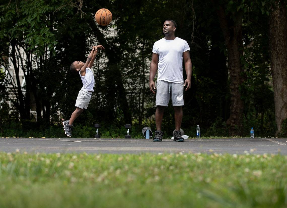 Theo Moody watches as his son, Legend, 5, practices shooting on the basketball courts at Walltown Park on Tuesday, June 13, 2023, in Durham, N.C.