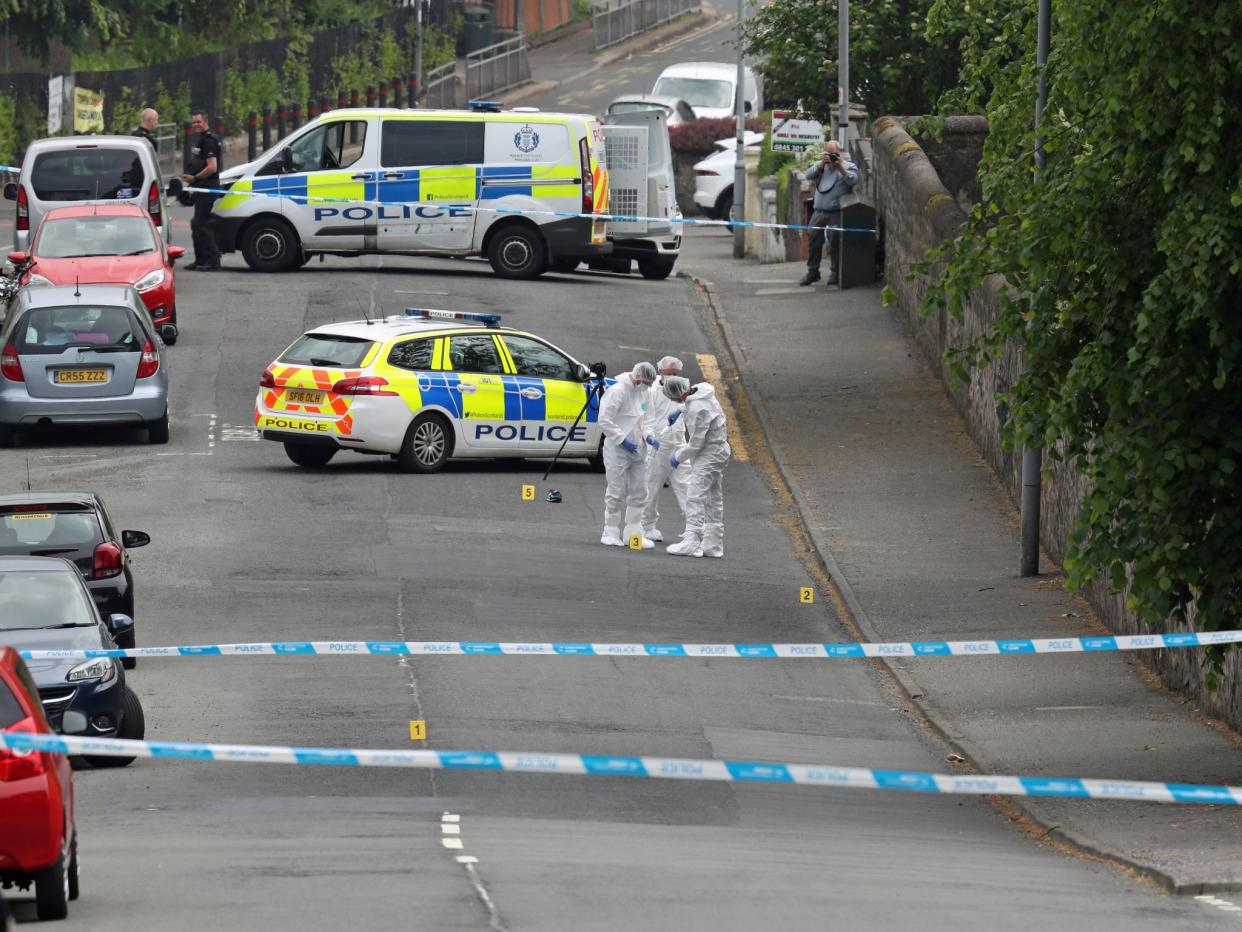 Forensic officers put a knife in an evidence bag as they investigate the scene of an incident in Gateside Gardens, Greenock, where two police officers were injured: PA