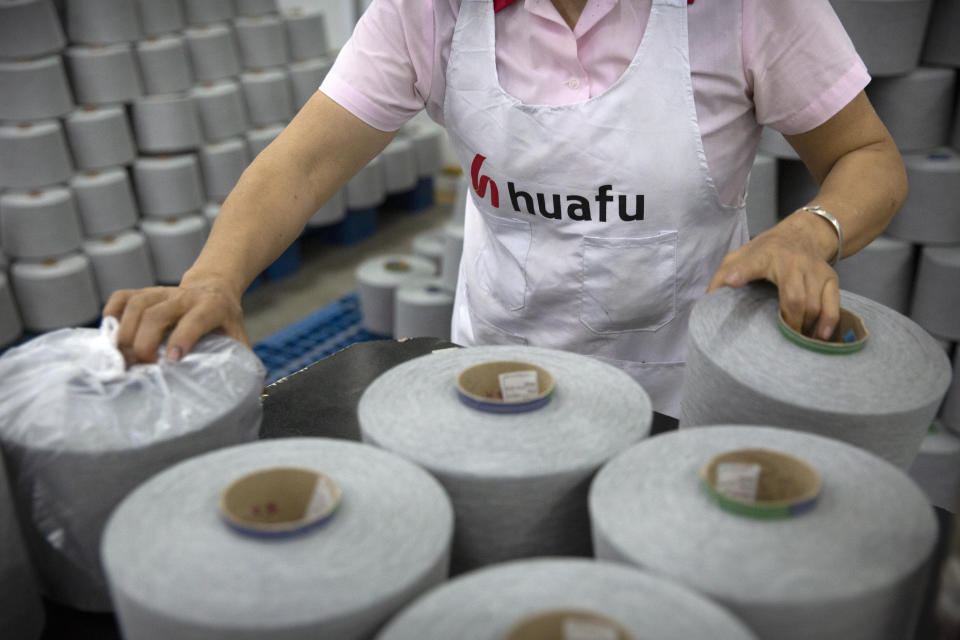 A worker packages spools of cotton yarn at a Huafu Fashion plant, as seen during a government organized trip for foreign journalists, in Aksu in western China's Xinjiang Uyghur Autonomous Region, Tuesday, April 20, 2021. A backlash against reports of forced labor and other abuses of the largely Muslim Uyghur ethnic group in Xinjiang is taking a toll on China's cotton industry, but it's unclear if the pressure will compel the government or companies to change their ways. (AP Photo/Mark Schiefelbein)