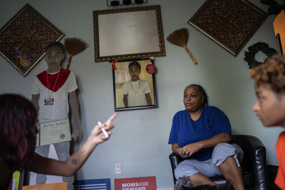 A life-size cutout and a portrait of Christian Gwynn decorate the family's home as his mother, Krista, center, and sisters, Victoria, 21, left, and Navada, 15, talk in the living room in Louisville, Ky., Monday, Aug. 28, 2023. Christian, 19, was killed in a drive-by shooting four blocks from home in December 2019. Just two years later, Victoria, then also 19, was shot and injured at a park on Louisville’s eastside. The 17-year-old friend she was there to meet was killed. (AP Photo/David Goldman)