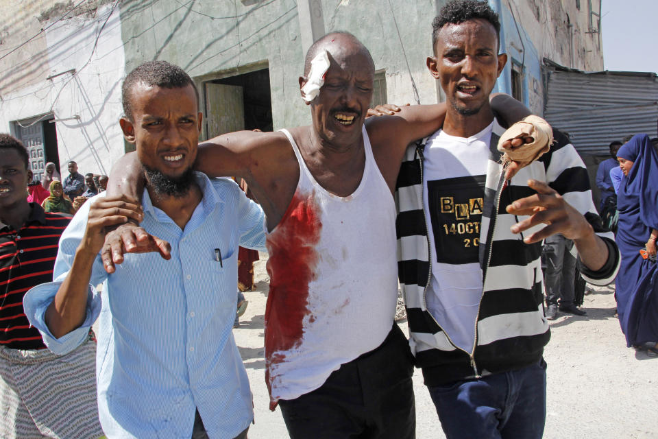 An injured man is assisted after being wounded in a bomb blast near the presidential palace in the capital Mogadishu, Somalia. Saturday, Dec. 22, 2018. Police say a suicide car bomb detonated near the presidential palace killing and wounding a number of people. (AP Photo/Farah Abdi Warsameh)