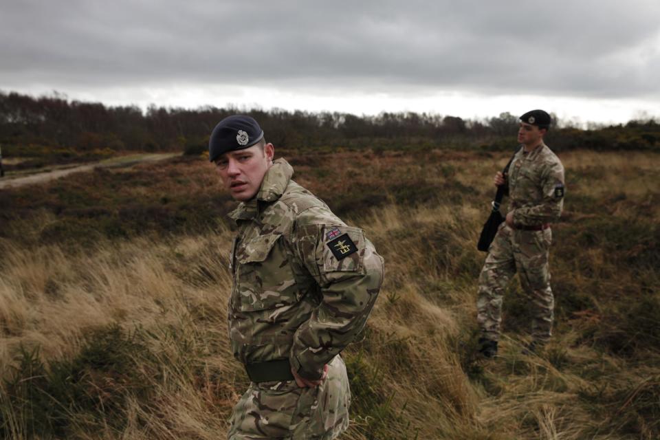 British army officers walk on an area with WW1 practise trenches in Gosport, southern England, Thursday, March 6, 2014. This overgrown and oddly corrugated patch of heathland on England’s south coast was once a practice battlefield, complete with trenches, weapons and barbed wire. Thousands of troops trained here to take on the Germany army. After the 1918 victory _ which cost 1 million Britons their lives _ the site was forgotten, until it was recently rediscovered by a local official with an interest in military history. Now the trenches are being used to reveal how the Great War transformed Britain _ physically as well as socially. As living memories of the conflict fade, historians hope these physical traces can help preserve the story of the war for future generations. (AP Photo/Lefteris Pitarakis)
