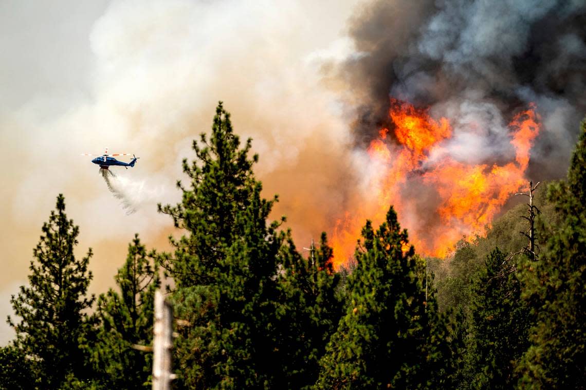 A helicopter drops water while battling the Oak Fire in Mariposa County, Calif., on Sunday, July 24, 2022.