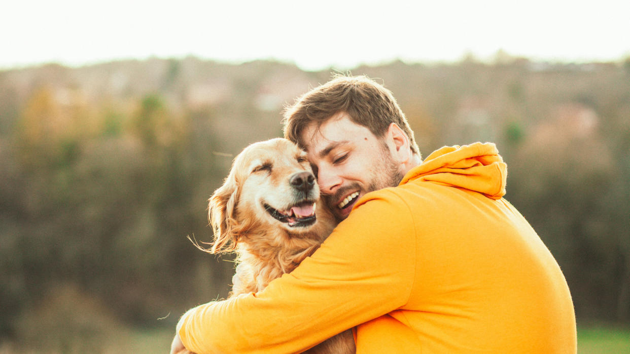  Man hugging his golden retriever. 