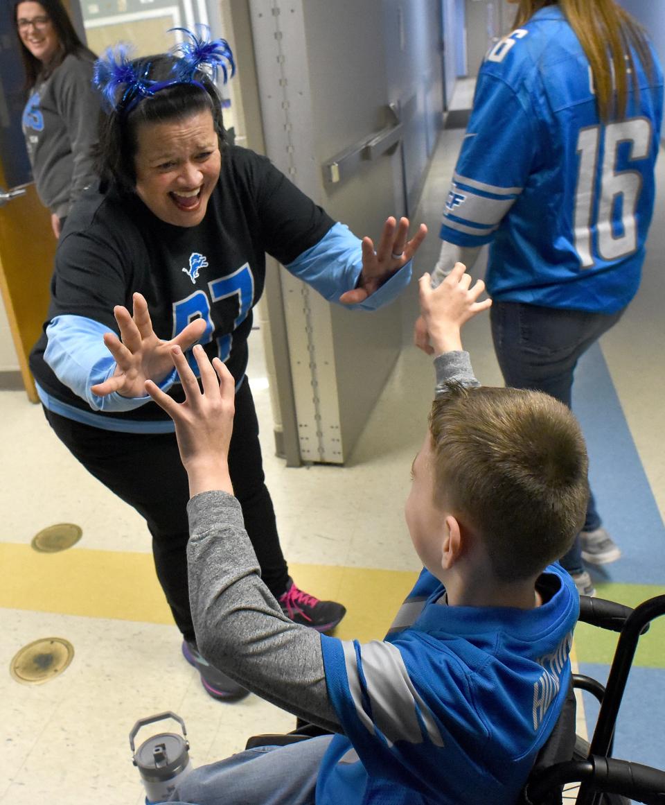 Barnes Elementary school principal Kirstie Mullins high-fives Conner Adcock Thursday, Detroit Lions Day at the school. ,