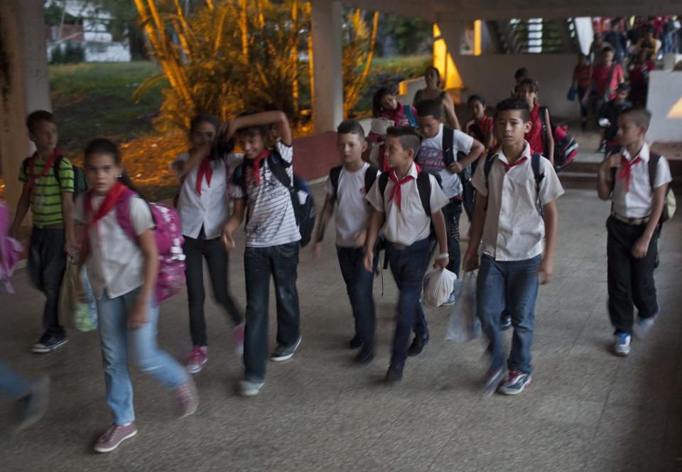 In this March 29, 2014 photo, children or "pioneers," wearing red neckerchiefs over white shirts walk through the Ernesto "Che" Guevara Palace, during festivities marking the anniversaries of the Organization of Cuban Pioneers and of the Union of Communist Youth in Havana, Cuba. Cuban schoolchildren are referred to as "pioneers," and the organization was founded in 1961 to encourage the values of education and social responsibility among children and adolescents. (AP Photo/Franklin Reyes)