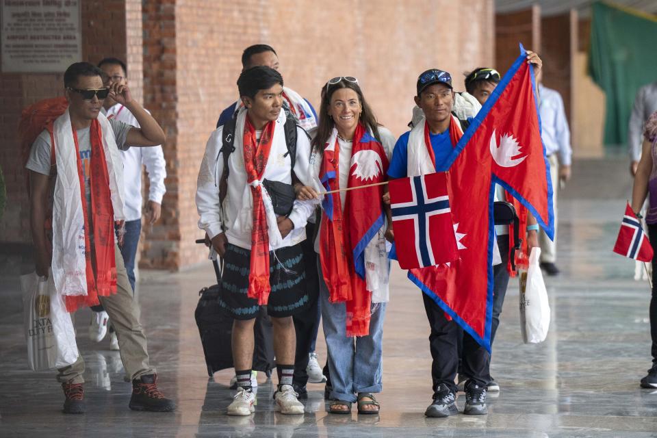 Norwegian woman mountain climber Kristin Harila, second right and her Nepali Sherpa guide Tenjen Sherpa, right who on Thursday set a new record by scaling the world's 14 highest peaks in 92 days arrive at the airport in Kathmandu, Nepal, Saturday, Aug.5, 2023. (AP Photo/Niranjan Shreshta)