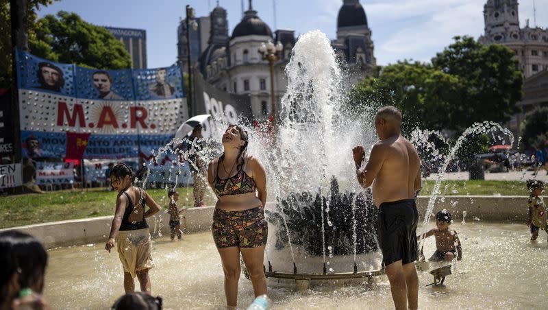 People cool off in a fountain, as a protest organized by a variety of social organizations takes place in the background, in Buenos Aires, Argentina, on Friday, March 3, 2023. Parts of South America are under an extreme heat wave in the middle of the winter. 