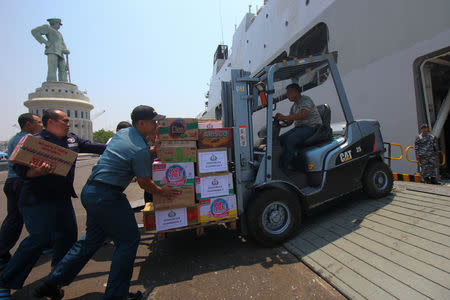 Indonesian navy push a fork-truck as they load packages of aid to distribute for victims of the earthquake and tsunami in Palu at Koarmada II port in Surabaya, East Java, Indonesia, October 2, 2018 in this photo taken by Antara Foto. Antara Foto/Didik Suhartono/ via REUTERS