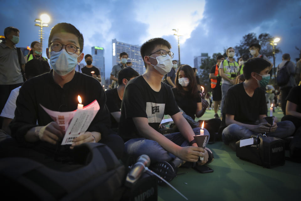 Hong Kong democracy activist Joshua Wong, center, holds a candle as he joins others for a vigil to remember the victims of the 1989 Tiananmen Square Massacre at Victoria Park in Causeway Bay, Hong Kong, Thursday, June 4,2020. China is tightening controls over dissidents while pro-democracy activists in Hong Kong and elsewhere try to mark the 31st anniversary of the crushing of the pro-democracy movement in Beijing's Tiananmen Square. (AP Photo/Kin Cheung)