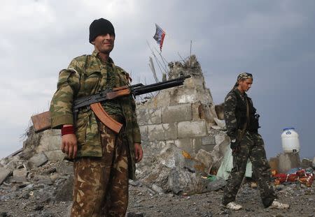 Pro-Russian separatists walk at a destroyed war memorial on Savur-Mohyla, a hill east of the city of Donetsk, August 28, 2014. REUTERS/Maxim Shemetov