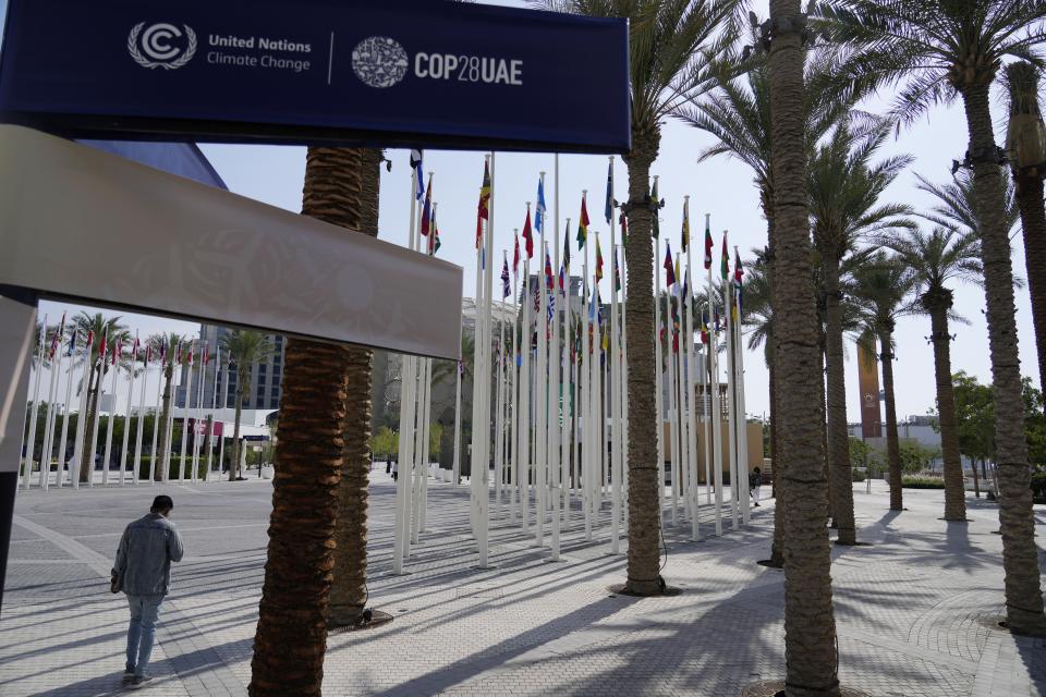 A person stands under a sign for the COP28 U.N. Climate Summit, Tuesday, Nov. 28, 2023, in Dubai, United Arab Emirates. (AP Photo/Rafiq Maqbool)