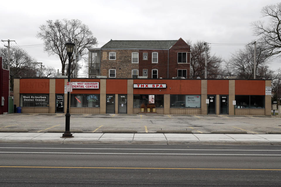 A parking lot in the Village of Oak Park, Ill., sits empty where small businesses are closed, Friday, March 20, 2020. There are at least three confirmed cases of COVID-19 in Oak Park, just nine miles from downtown Chicago, where the mayor has ordered residents to shelter in place. With so few tests available, surely there are others, says Tom Powers, spokesman for the village of about 52,000 in a metropolitan area with millions. (AP Photo/Charles Rex Arbogast)