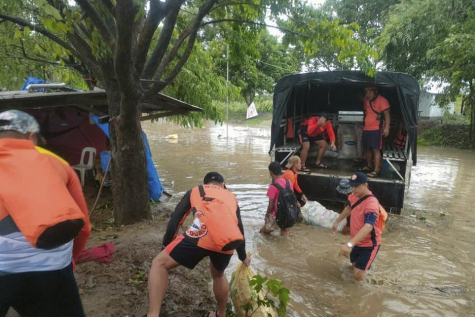 In this photo provided by the Philippine Coast Guard, rescuers carry food as they move them to safer grounds in Tuguegarao, Cagayan province, northern Philippines on Tuesday Aug. 23, 2022. A tropical storm lashed the northern Philippines with strong wind and rain Tuesday, injuring at least two people and prompting the president to close schools and government offices in the capital and outlying provinces. (Philippine Coast Guard via AP)