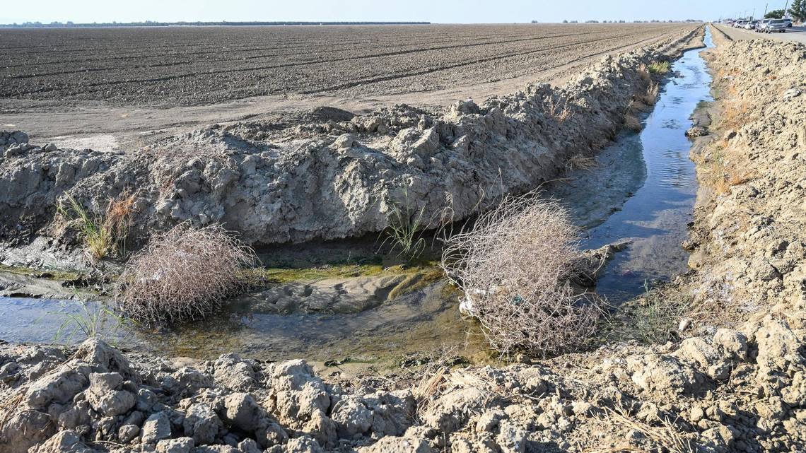 A small amount of water flows in a ditch near an empty field at the edge of the town in Huron on Thursday, Sept. 15, 2022. Many fields around the southern San Joaquin Valley have been left fallow as the drought continues, drying up work for families in the process.
