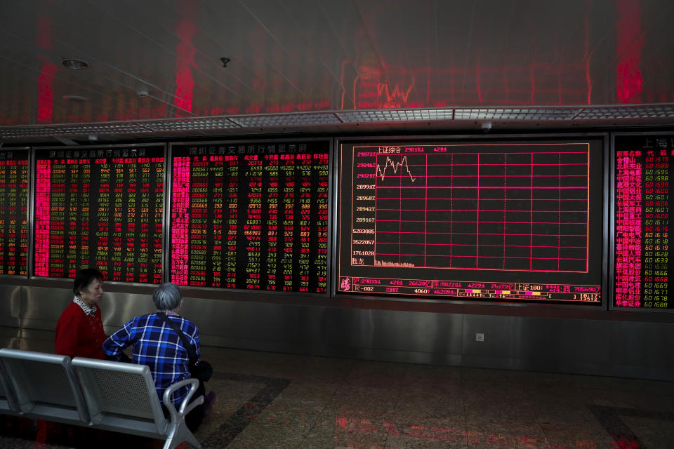 Chinese women chat with each other near an electronic screen displaying stock prices at a brokerage house in Beijing, Friday, Dec. 6, 2019. Shares swung higher in Asia on Friday after a wobbly day of trading on Wall Street as investors awaited a U.S. government jobs report and kept an eye out for developments in China-U.S. trade talks. (AP Photo/Andy Wong)