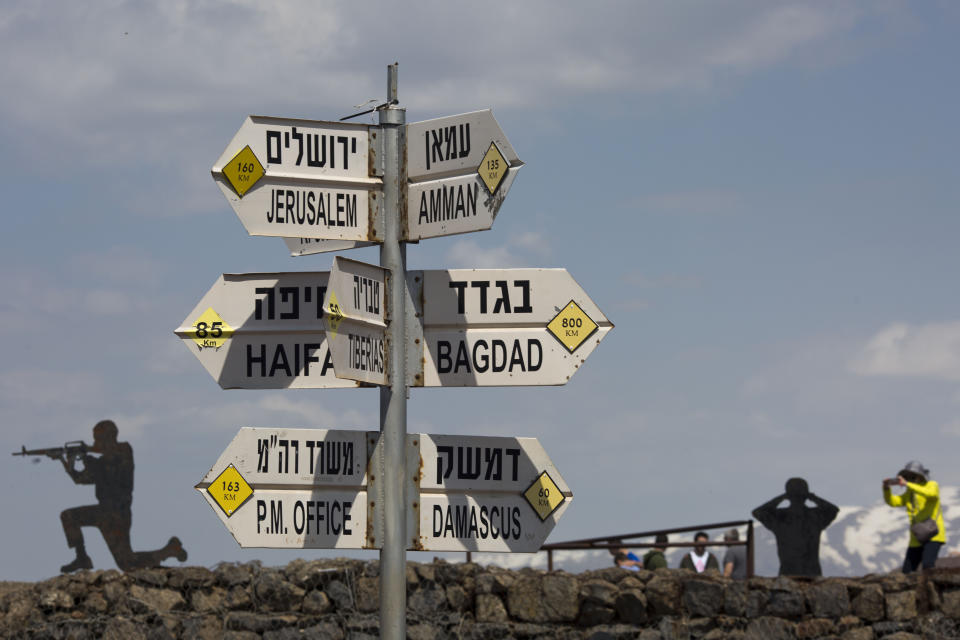 Tourists take photographs next to a mock road sign for Damascus, the capital of Syria, and other capitals and cities and a cutout of a soldiers, in an old outpost in the Israeli controlled Golan Heights near the border with Syria, Friday, March 22, 2019. President Donald Trump abruptly declared Thursday the U.S. will recognize Israel's sovereignty over the disputed Golan Heights, a major shift in American policy that gives Israeli Prime Minister Benjamin Netanyahu a political boost a month before what is expected to be a close election.(AP Photo/Ariel Schalit)