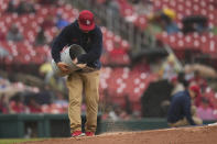 A member of the Busch Stadium grounds crew works to make the mound playable during a steady rain during the fourth inning of a baseball game between the St. Louis Cardinals and the Philadelphia Phillies Wednesday, April 10, 2024, in St. Louis. (AP Photo/Jeff Roberson)