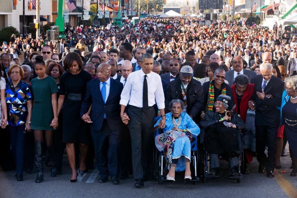 President Barack Obama, center, walks as he holds hands with Amelia Boynton Robinson, who was beaten during "Bloody Sunday," as they and the first family and others including Rep. John Lewis, D-Ga,, left of Obama, walk across the Edmund Pettus Bridge in Selma, Ala. for the 50th anniversary of "Bloody Sunday," a landmark event of the civil rights movement, Saturday, March 7, 2015. From front left are Marian Robinson, Sasha Obama. first lady Michelle Obama. Obama, Boynton and Adelaide Sanford, also in wheelchair. 