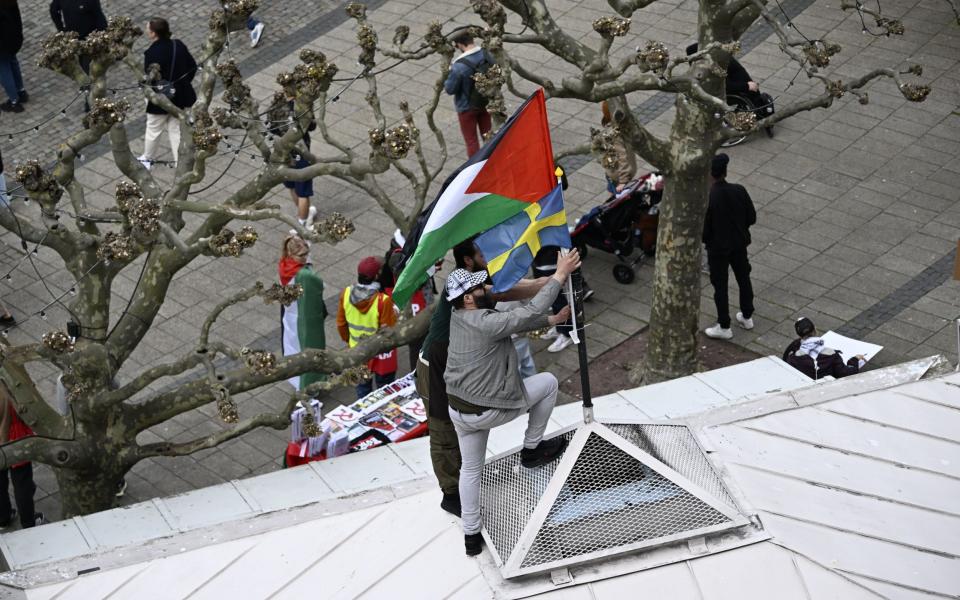 Activists display a Swedish flag alongside the Palestinian flag on a rooftop in Malmo