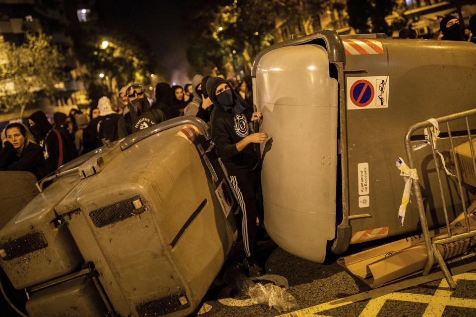 Demonstrators take shelter behind a barricade during clashes with police in Barcelona, Spain, Wednesday, Oct. 16, 2019. Spain's government said Wednesday it would do whatever it takes to stamp out violence in Catalonia, where clashes between regional independence supporters and police have injured more than 200 people in two days. (AP Photo/Bernat Armangue)