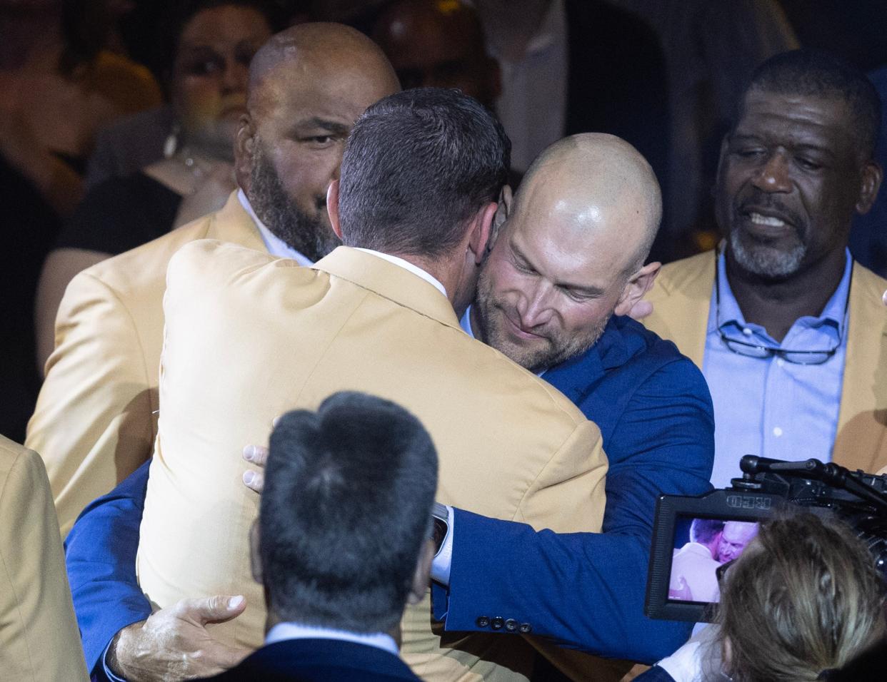 Enshrinees hug at the 2023 Hall of Fame Enshrinees' Gold Jacket Dinner at Canton Memorial Civic Center on Friday.