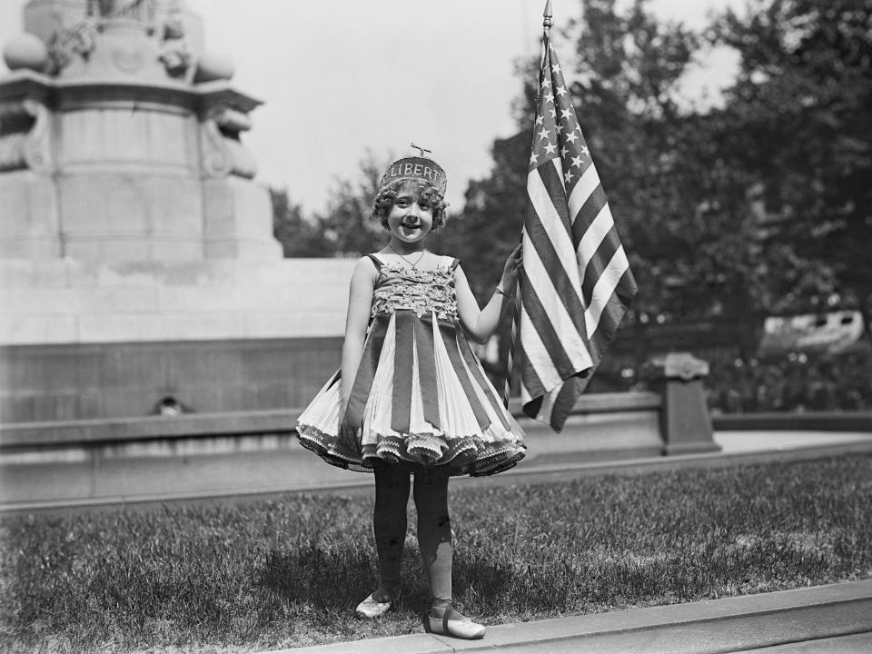 A young girl holds up an American flag in Washington, DC, during the July 4th celebrations in 1916.