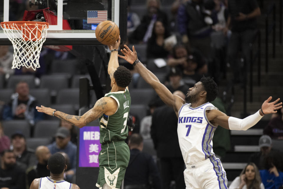 Milwaukee Bucks guard George Hill (3) lays the ball up past Sacramento Kings forward Chimezie Metu (7) during the first quarter of an NBA basketball game in Sacramento, Calif., Wednesday, March 16, 2022. (AP Photo/José Luis Villegas)