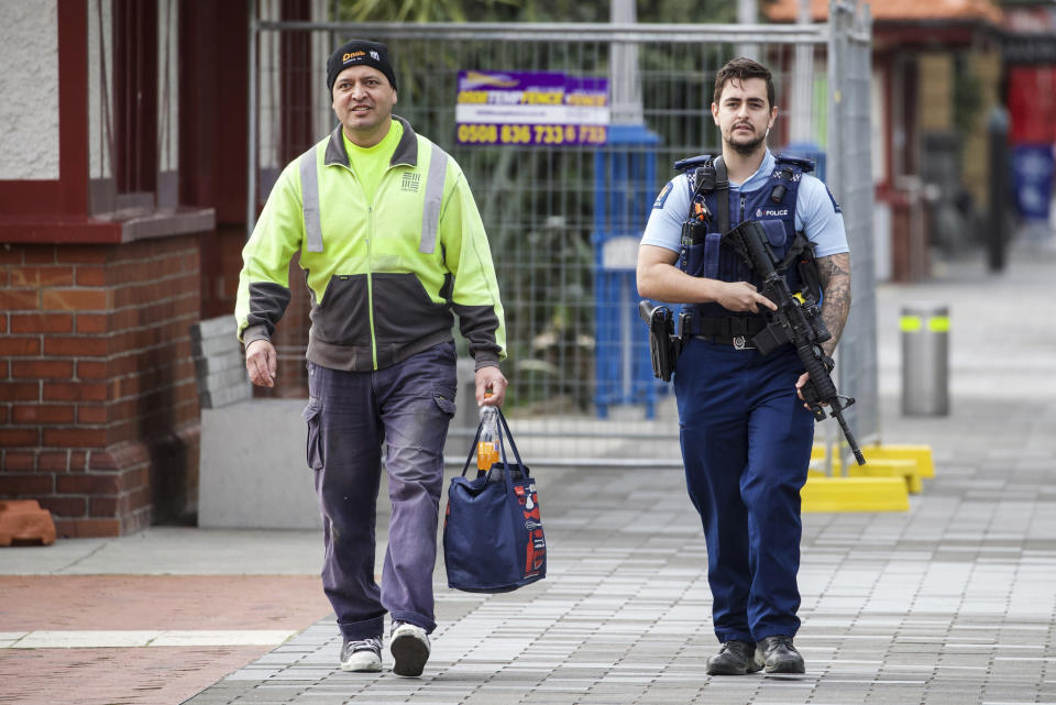 A construction worker is escorted by police in the central business district following a shooting in Auckland, New Zealand, Thursday, July 20, 2023. New Zealand police are responding to reports that a gunman has fired shots in a building in downtown Auckland. (Jason Oxenham/NZ Herald via AP)