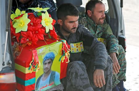 Fighters of Syrian Democratic Forces sit next to the coffin of their comrade killed by the Islamic State militants at the frontline in Deir al-Zour, during a funeral in Kobani, Syria October 14, 2017. REUTERS/Erik De Castro