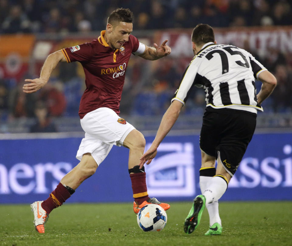 AS Roma's Francesco Totti, left, tries to dribble past Udinese's Thomas Heurtaux during a Serie A soccer match between AS Roma and Udinese in Rome's Olympic stadium, Monday, March 17, 2014. (AP Photo/Gregorio Borgia)