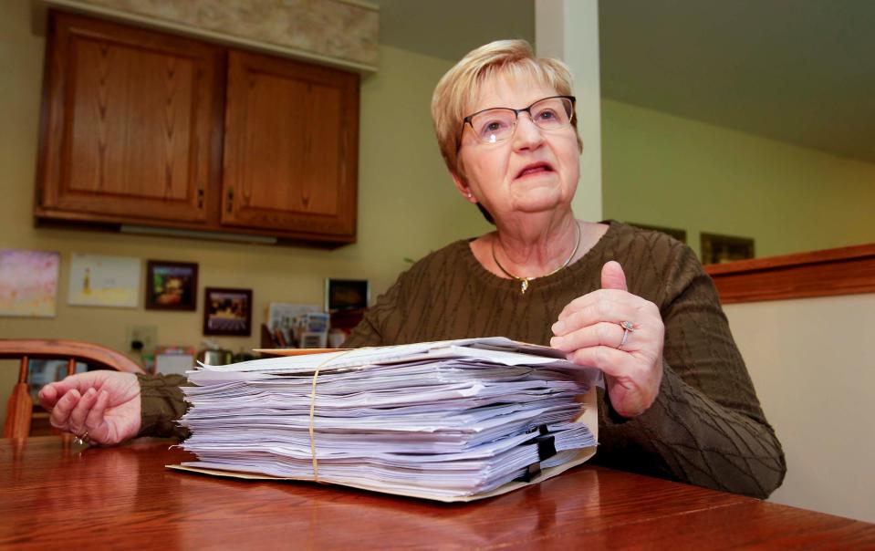 Mary Sommersberger, of Sheboygan, sits at her kitchen table Oct. 21, 2022, with her file of medical bills and statements that arose when she tripped and fell on a pothole outside of her home, dislocating her shoulder, in Sheboygan, Wis. Sommersberger said that the city of Sheboygan has denied her injury claim, saying the pothole had not been reported.