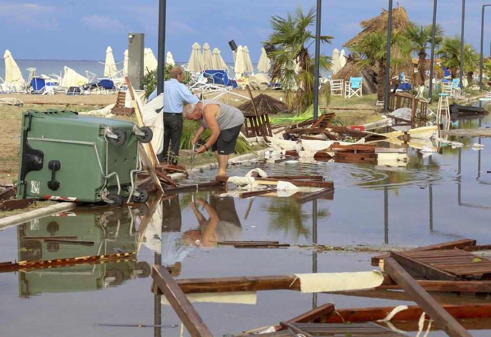 Two men search in debris after a storm at Nea Plagia village in Halkidiki region, northern Greece on Thursday, July 11, 2019. A powerful storm hit the northern Halkidiki region late Wednesday, toppling trees and power pylons, cutting power and blocking roads. (Giannis Moisiadis/InTime News via AP)