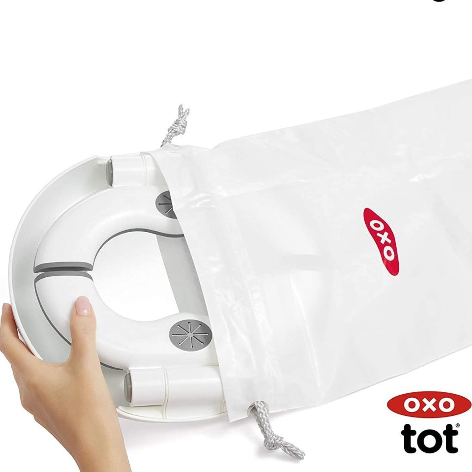 Hand holding an OXO tot product with a travel bag, emphasizing portability for shoppers