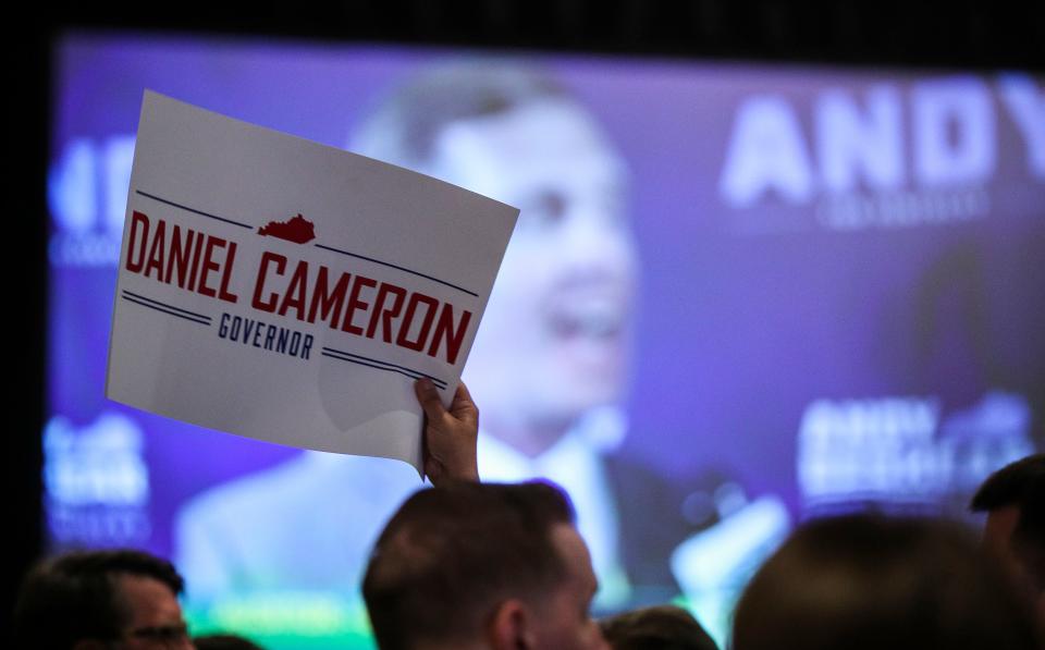 A Daniel Cameron supporter waves a sign as opponent and Democrat Gov. Andy Beshear speaks during his victory speech at the Galt House Hotel in Louisville, Ky. Cameron won the 2023 Kentucky Republican primary.