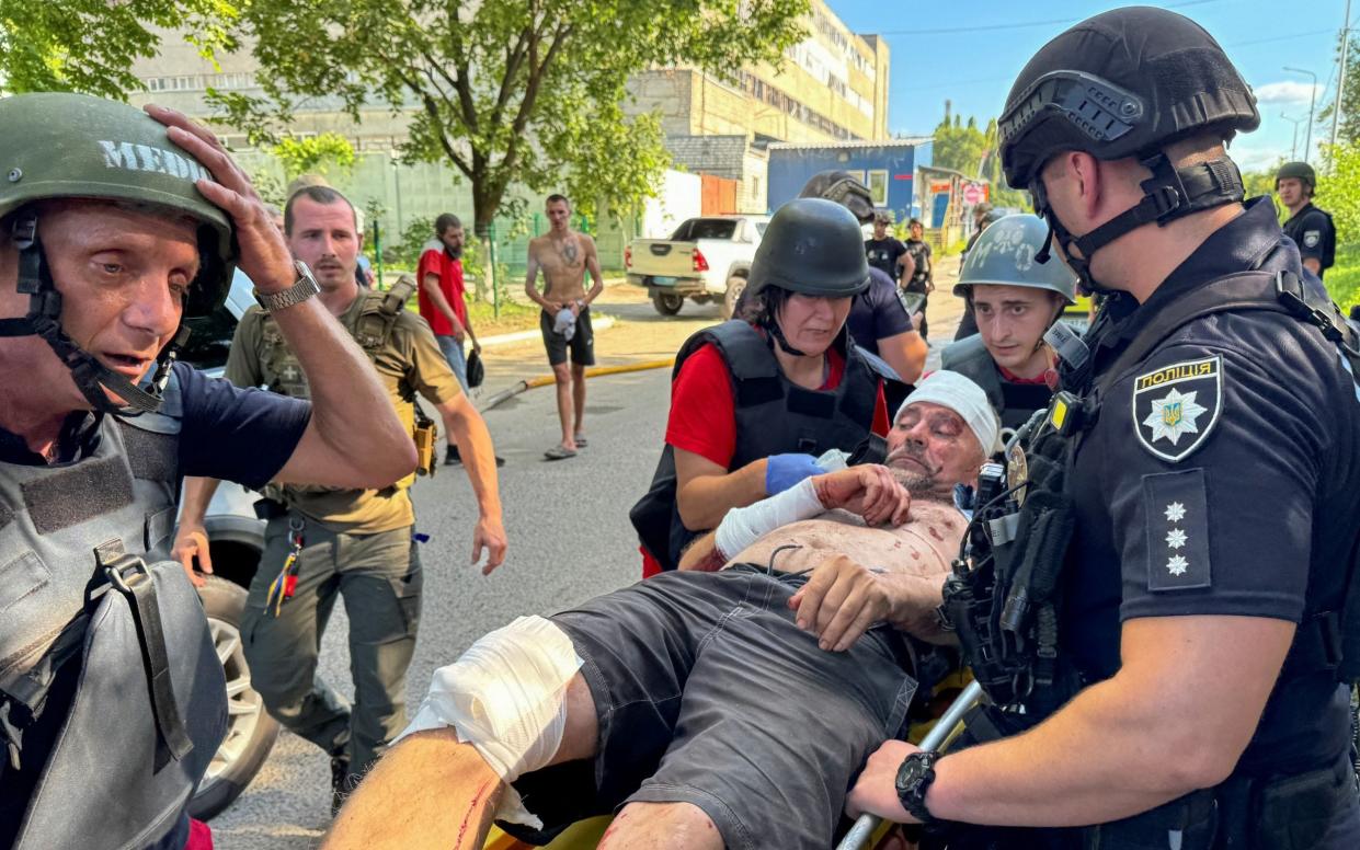 Police officers and paramedics carry an injured man at a site of a Russian air strike, in Kharkiv, Ukraine June 30