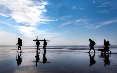 Pilgrims carry crosses to the Holy Island of Lindisfarne in Northumberland during the annual Christian Easter pilgrimage - Credit: Danny Lawson/PA Wire