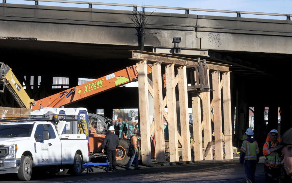 Crews continue to clear debris and shore up a stretch of Interstate 10, Tuesday morning Nov. 14, 2023, in Los Angeles. It will take at least three weeks to repair the Los Angeles freeway damaged in an arson fire, the California Gov. Gavin Newsom said Tuesday, leaving the city already accustomed to soul-crushing traffic without part of a vital artery that serves hundreds of thousands of people daily. (Dean Musgrove/The Orange County Register via AP)