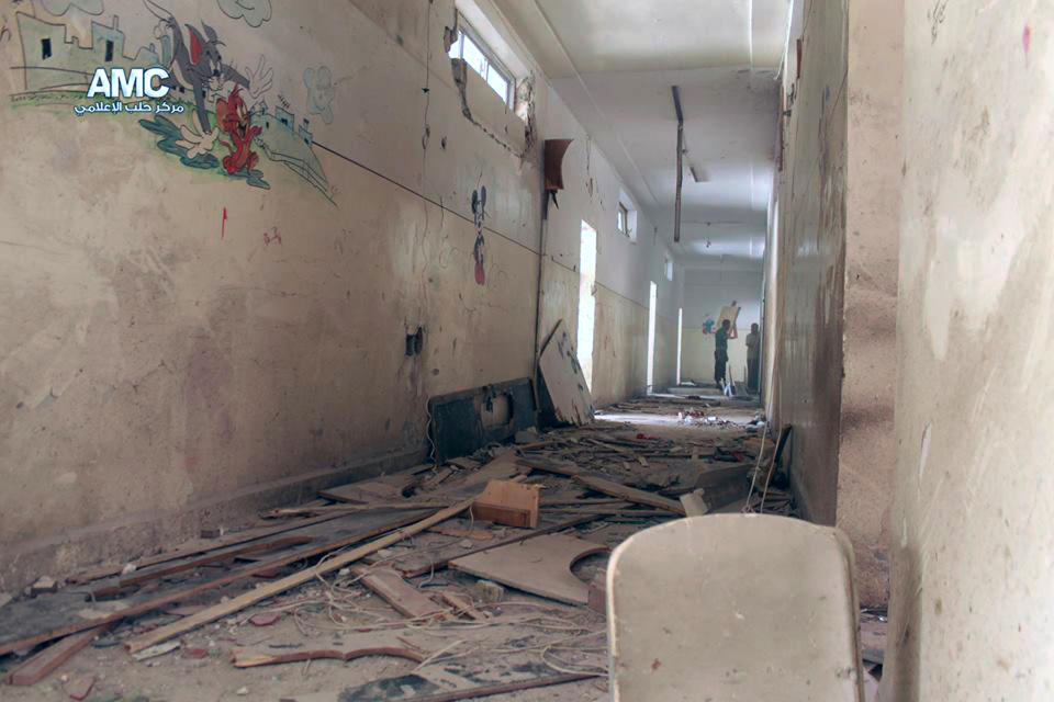 This photo provided by the anti-government activist group Aleppo Media Center (AMC), which has been authenticated based on its contents and other AP reporting, shows two Syrian men standing inside a school that was hit by a Syrian government air strike in Aleppo, Syria, Wednesday, April. 30, 2014. Many people were killed and wounded, including several children, activists reported. (AP Photo/Aleppo Media Center AMC)