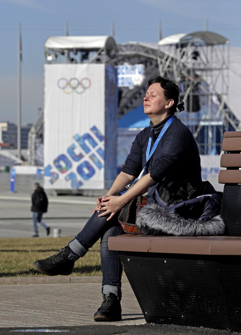 In this Wednesday, Feb. 12, 2014, photo, a woman enjoys some warm sunlight in the Olympic Park at the 2014 Winter Olympics, in Sochi, Russia. Temperatures were near 60 degrees Fahrenheit in Sochi on Wednesday. (AP Photo/Morry Gash)